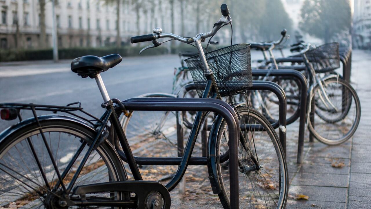 Vélos ordinaires attachés à un arceau dans une rue calme au matin